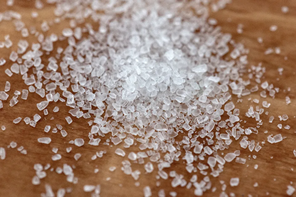 Coarse white sea salt crystals scattered on a wooden board
